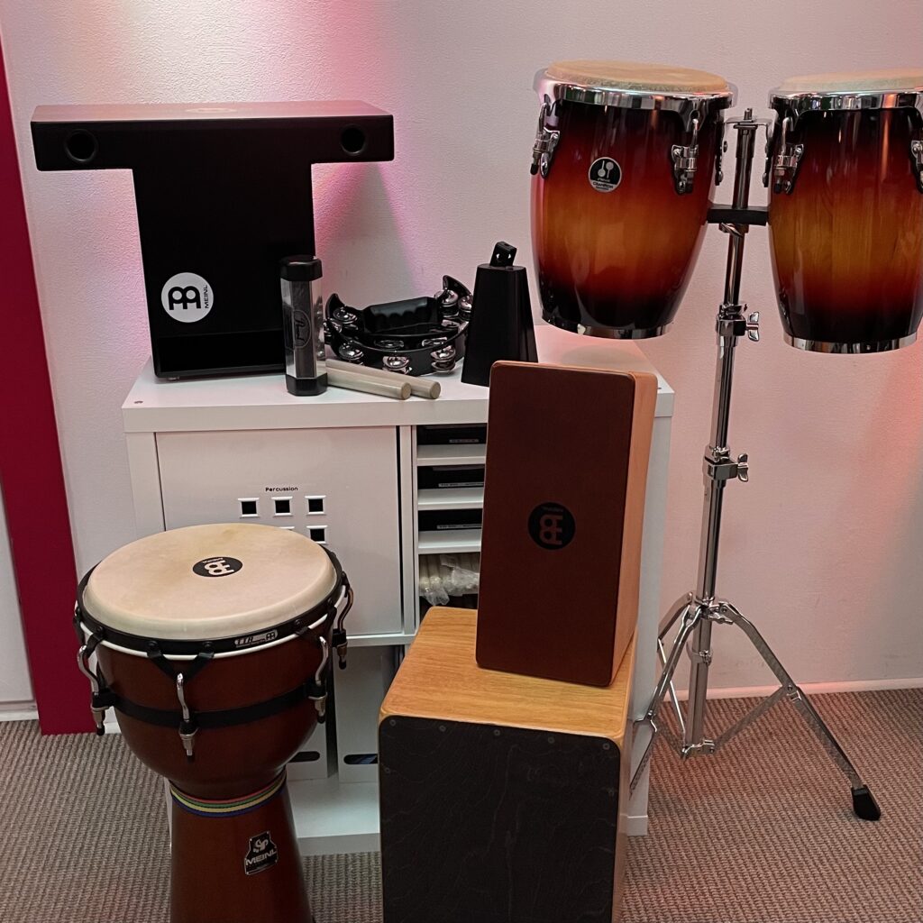 Dieses Bild zeigt verschiedene Percussion Instrumente Cajon, Djembe, Conga, Slaptop Cajon, Bongo, Shaker, Cowbell, Clave, Schellenkranz